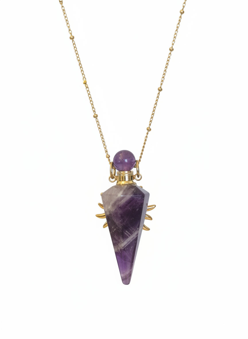 Amethyst pendulum perfume bottle necklace on a light fabric background