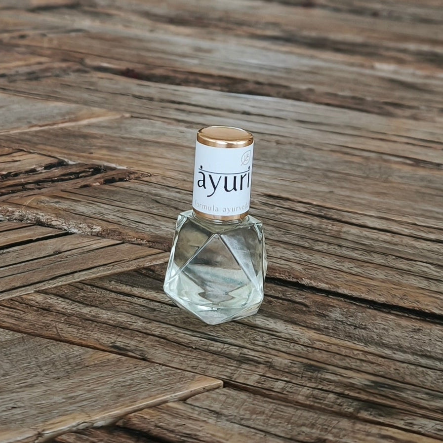 hand blended aroma oil roller bottle with a label on a wooden table in a room with furniture and decor.